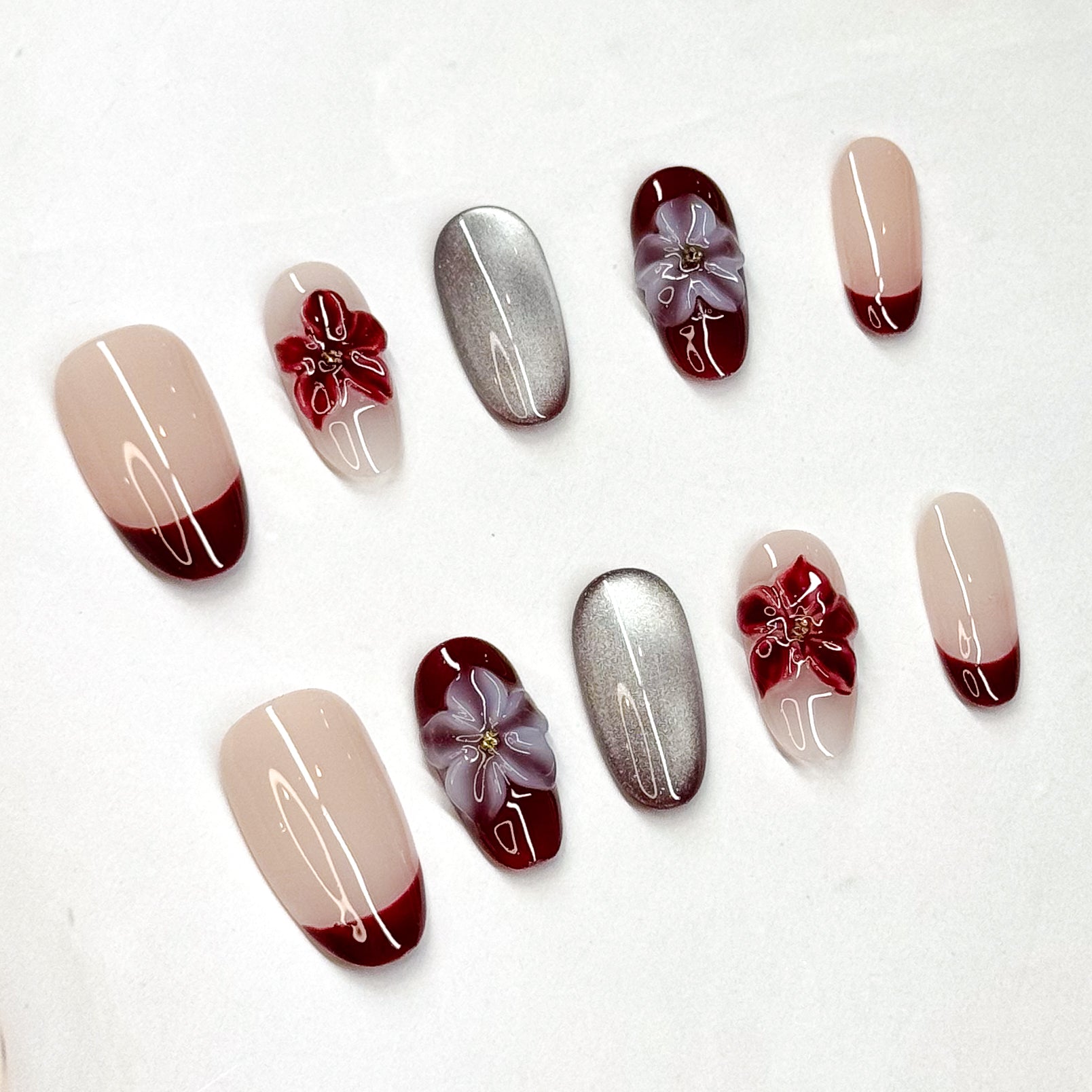 • Rich Contrast: Wine red French tips paired with nude bases for a chic finish.
• Metallic Accent: Mirror-like silver nails for a modern luxe edge.
• 3D Florals: Handcrafted gel flowers in crimson and lilac for depth and charm.
• Almond Shape: Elongates the fingers while staying feminine and refined.
• Handmade & Reusable: Durable, salon-quality design made with care.