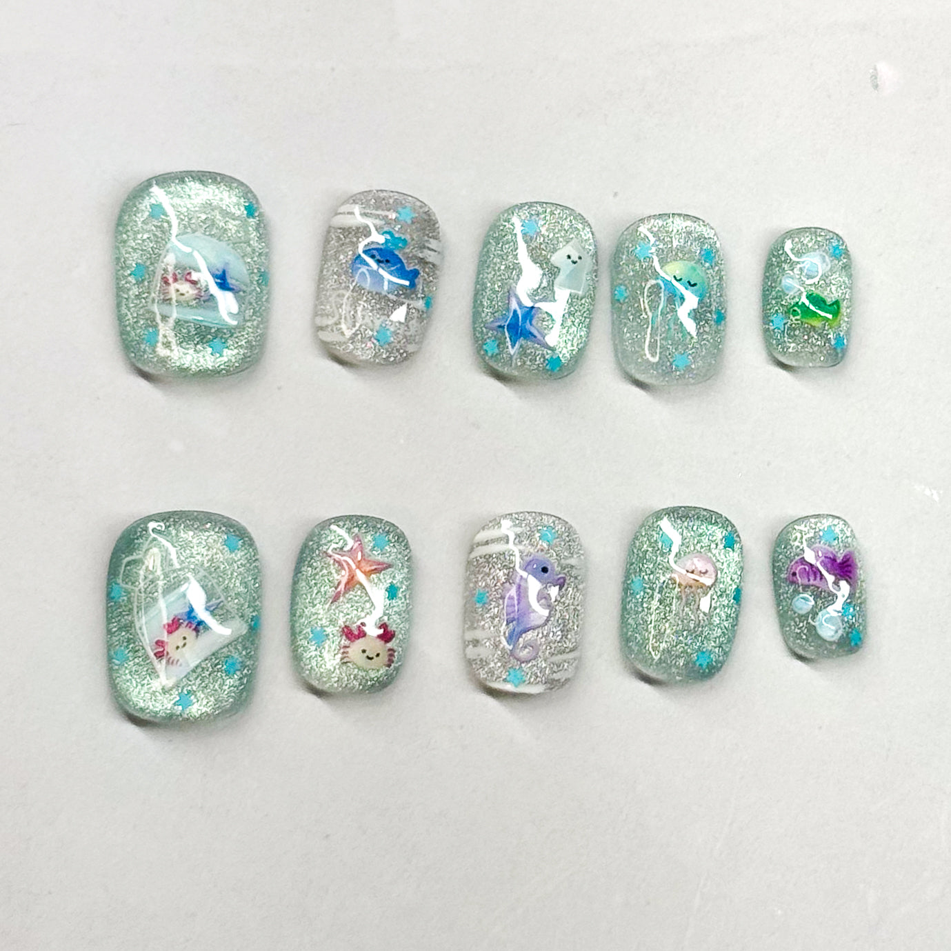 • Sparkling Base: Glittery aqua + silver backdrop with a dreamy ocean glow.
• Sea Life Accents: Whimsical marine designs — seahorse, jellyfish, dolphins, and more.
• Cute & Playful: Fun pops of color like purple, coral, and blue for a lively touch.
• Short Square Shape: Easy to wear and practical while still eye-catching.
• Handmade & Reusable: Crafted with 3D gel for durability and reusability.