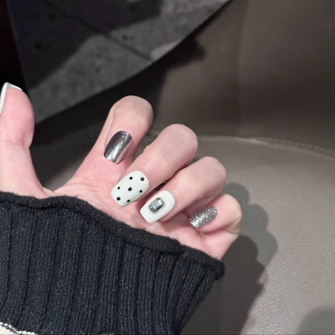 Break the rules of classic style with Polka Punk Chic Press-On Nails, a bold and playful combination of monochrome polka dots, metallic silver accents, and geometric embellishments. This eye-catching set features a short square shape with a glossy finish, blending retro charm with a futuristic edge. Perfect for those who dare to stand out, Polka Punk Chic brings a playful yet rebellious statement to your nails.