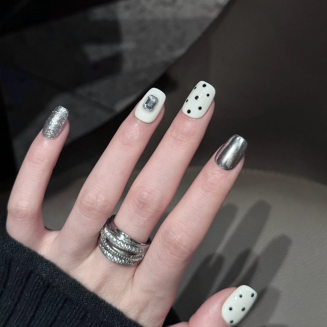 Break the rules of classic style with Polka Punk Chic Press-On Nails, a bold and playful combination of monochrome polka dots, metallic silver accents, and geometric embellishments. This eye-catching set features a short square shape with a glossy finish, blending retro charm with a futuristic edge. Perfect for those who dare to stand out, Polka Punk Chic brings a playful yet rebellious statement to your nails.