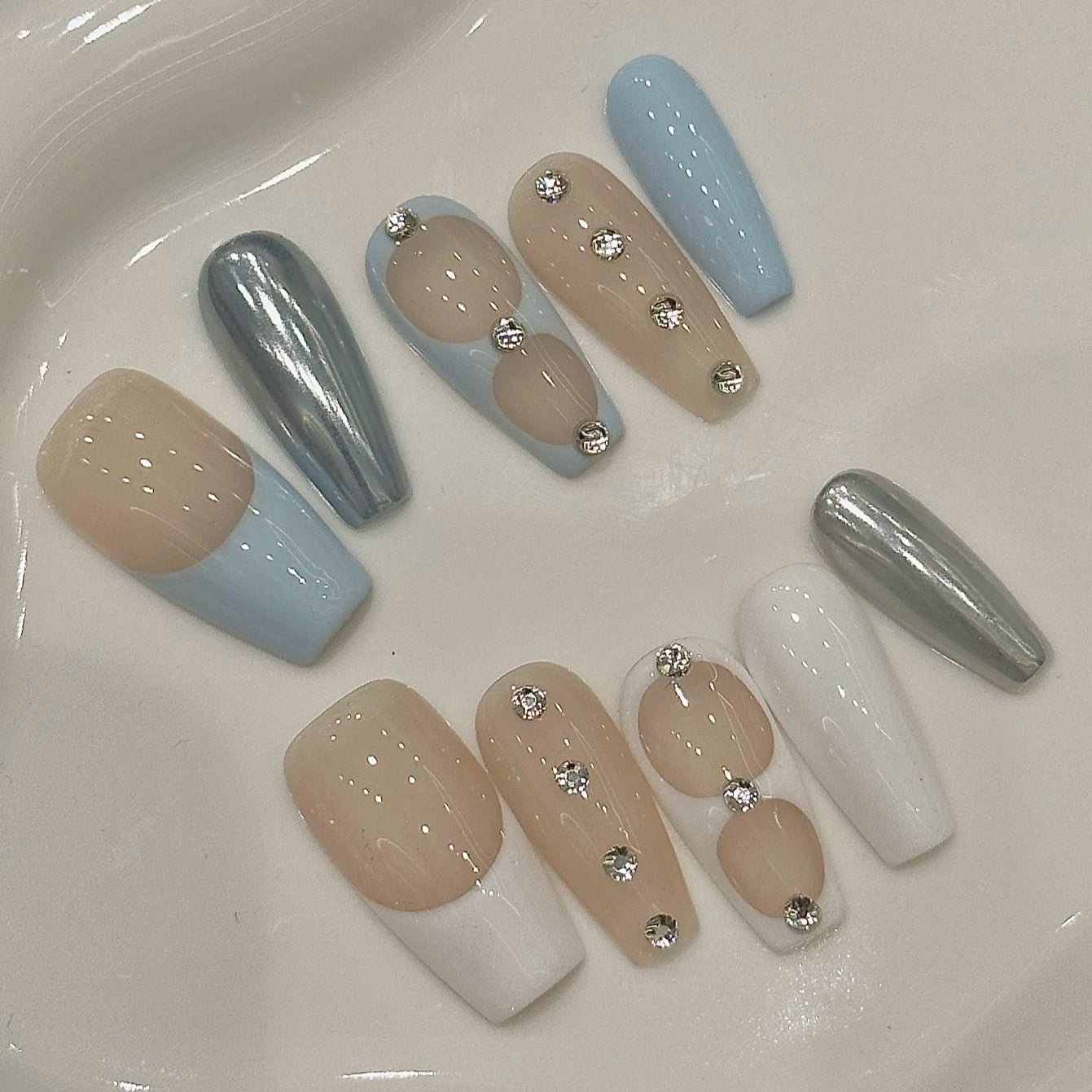 Serene Luxe Press-On Nails embody a perfect blend of minimalist sophistication and modern elegance. Featuring soft nude, baby blue, crisp white, and metallic silver accents, this set offers a dreamy, polished look for any occasion.