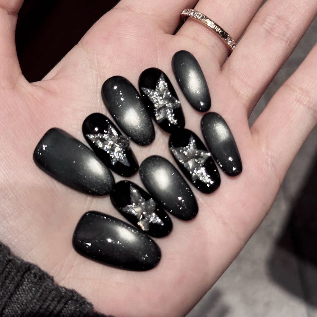 Starlit Shadows Press-On Nails capture the mystique of a starry night sky with a mesmerizing cat-eye effect that shimmers like cosmic dust. Accented with 3D silver star embellishments, these nails create a celestial and ethereal vibe that’s both elegant and edgy.