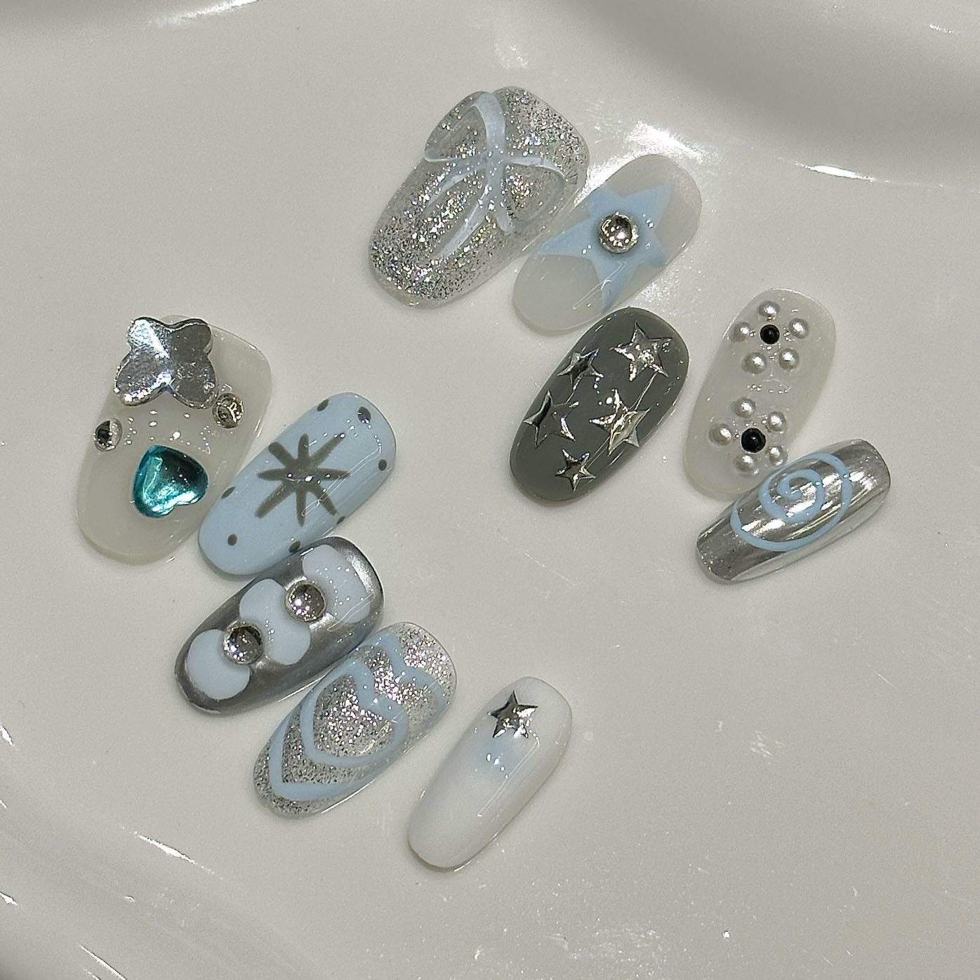 Stellar Twinkle Press-On Nails are a dreamy fusion of soft silver, icy blue, and celestial white, perfectly capturing the essence of a starlit sky. This set features a delightful mix of glittering star motifs, metallic accents, and whimsical swirl designs, bringing a magical and playful vibe to your fingertips.